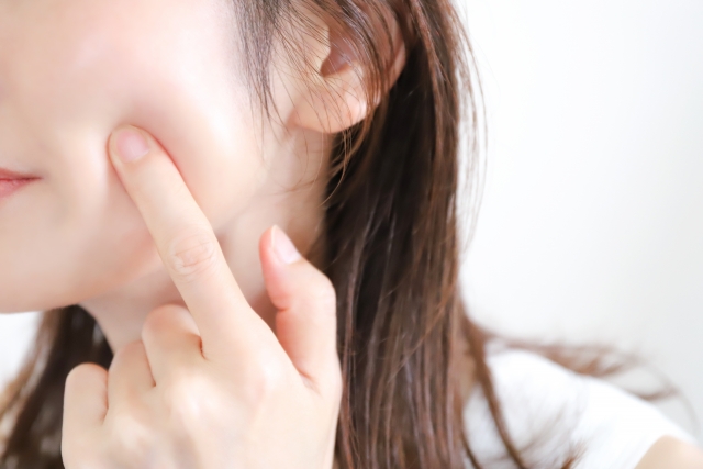 ハリや弾力のある頬を指で押す女性